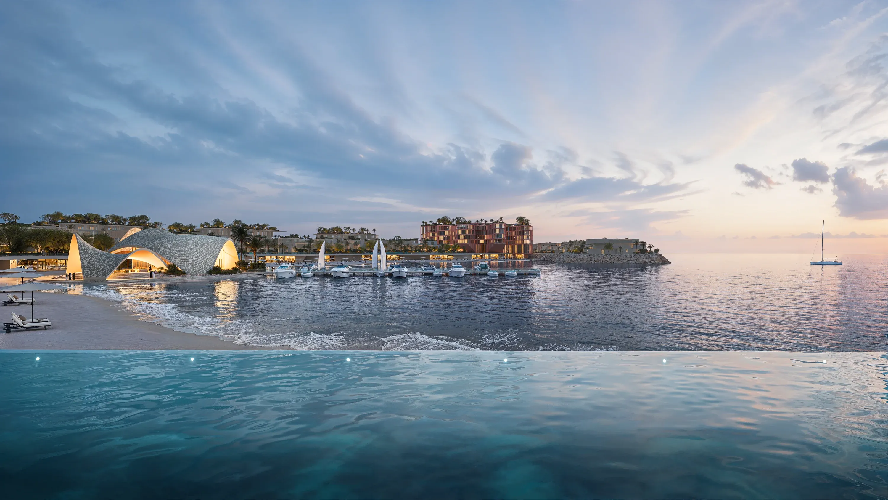 A beach club pool above the sea at Mira Coral Bay at dusk