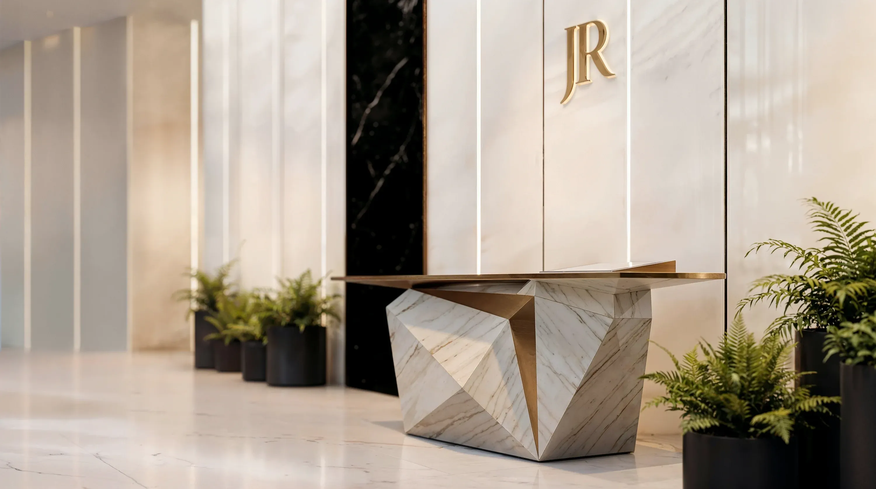 Der facettierte Marmortresen des Concierge in der Lobby von Richmond Residences, dahinter das beleuchtete Monogramm